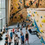 Kletternde in einer modernen Boulderhalle mit bunten Griffen und Volumen