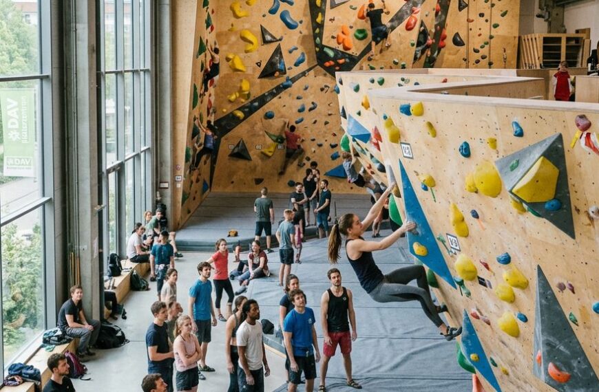 Kletternde in einer modernen Boulderhalle mit bunten Griffen und Volumen